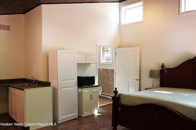 bedroom with a baseboard heating unit, visible vents, and a sink