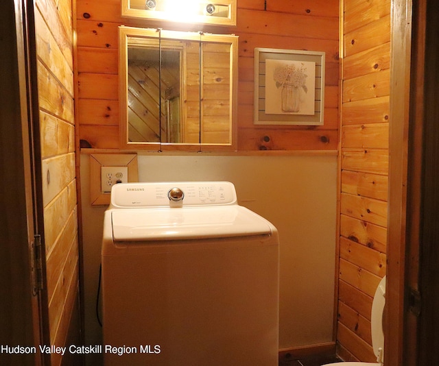 bathroom featuring washer / dryer and wooden walls