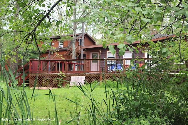 back of house featuring a lawn and a wooden deck