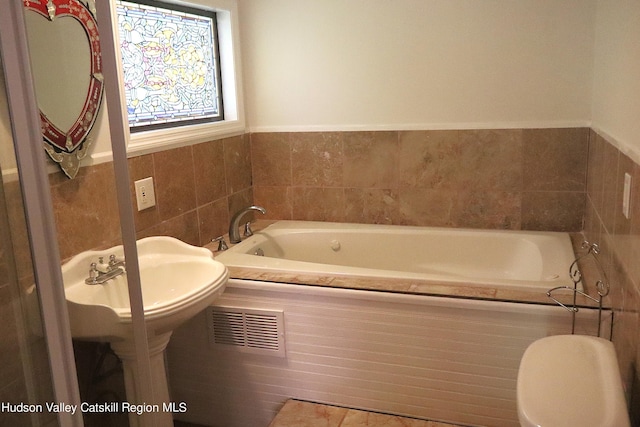 full bathroom featuring toilet, tile walls, visible vents, and a bath