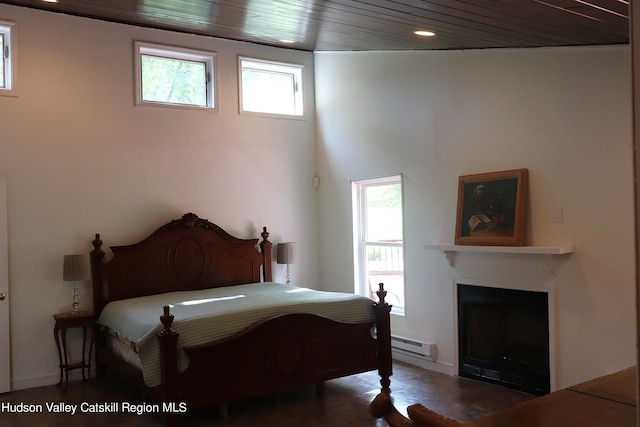 bedroom with wooden ceiling, multiple windows, a baseboard heating unit, and a fireplace