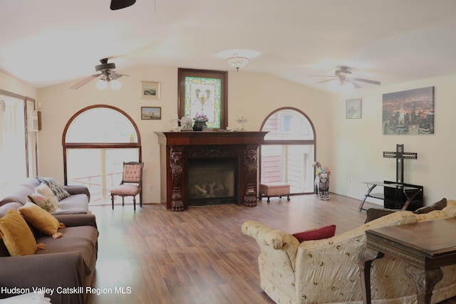 living room with a wealth of natural light, vaulted ceiling, ceiling fan, and wood finished floors