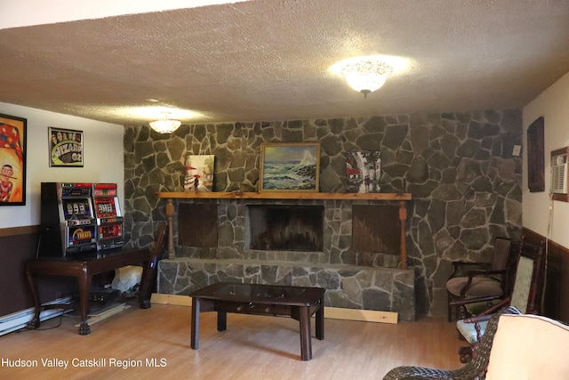 sitting room featuring a textured ceiling, a stone fireplace, and wood finished floors