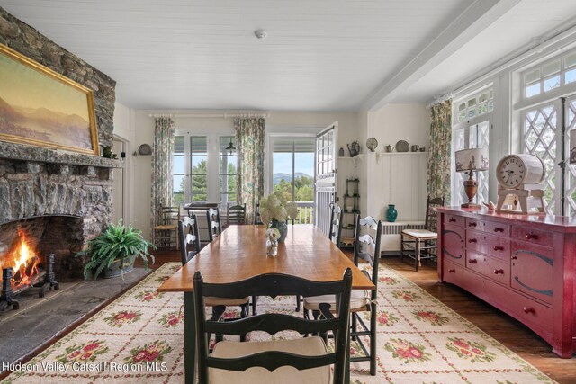 dining space with french doors, hardwood / wood-style flooring, and a stone fireplace