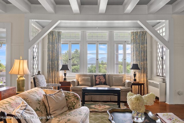 living room featuring coffered ceiling, crown molding, beam ceiling, wood-type flooring, and radiator heating unit