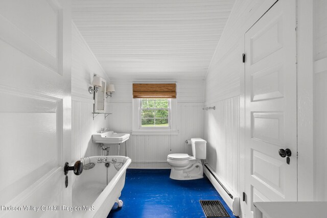 bathroom with a bath, a baseboard heating unit, vaulted ceiling, toilet, and concrete flooring