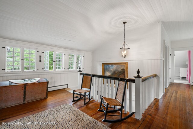 hallway featuring wood walls, dark hardwood / wood-style floors, lofted ceiling, and a baseboard heating unit