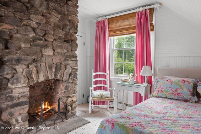 bedroom featuring a stone fireplace and lofted ceiling