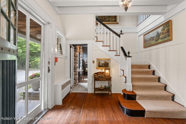 entrance foyer with beam ceiling, wood walls, plenty of natural light, and hardwood / wood-style flooring