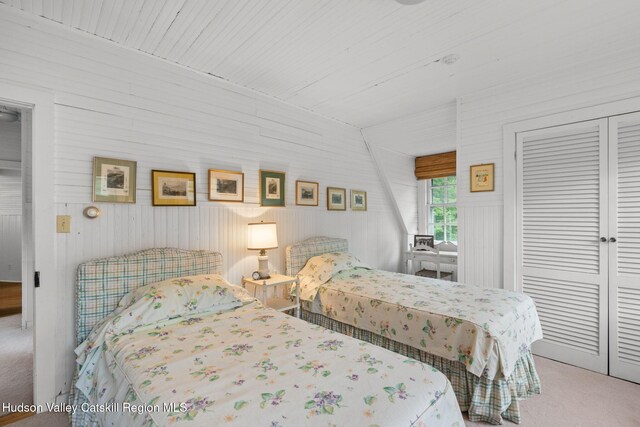 carpeted bedroom with a closet and wooden walls