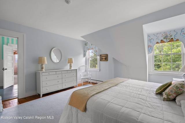 bedroom featuring a baseboard heating unit and hardwood / wood-style flooring