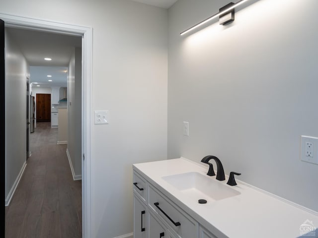 bathroom featuring wood finished floors, baseboards, recessed lighting, and vanity