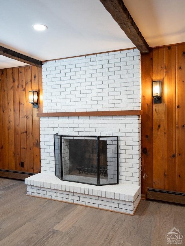 detailed view of beamed ceiling, a brick fireplace, wood finished floors, wood walls, and baseboard heating