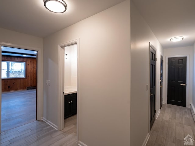 corridor with light wood-type flooring and baseboards