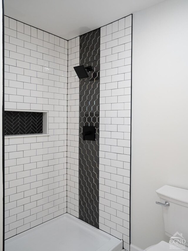 full bathroom with a tile shower and toilet