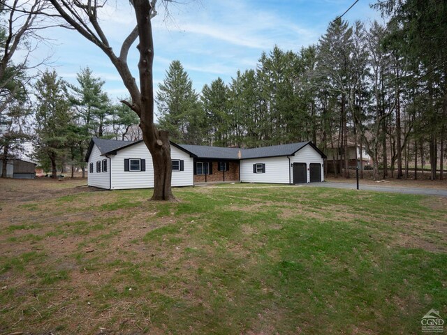 view of front of home featuring asphalt driveway, a garage, and a front lawn