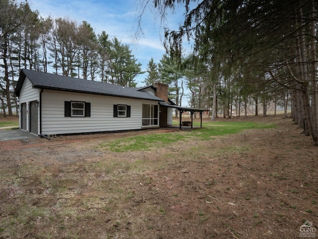 rear view of property with a chimney and a garage
