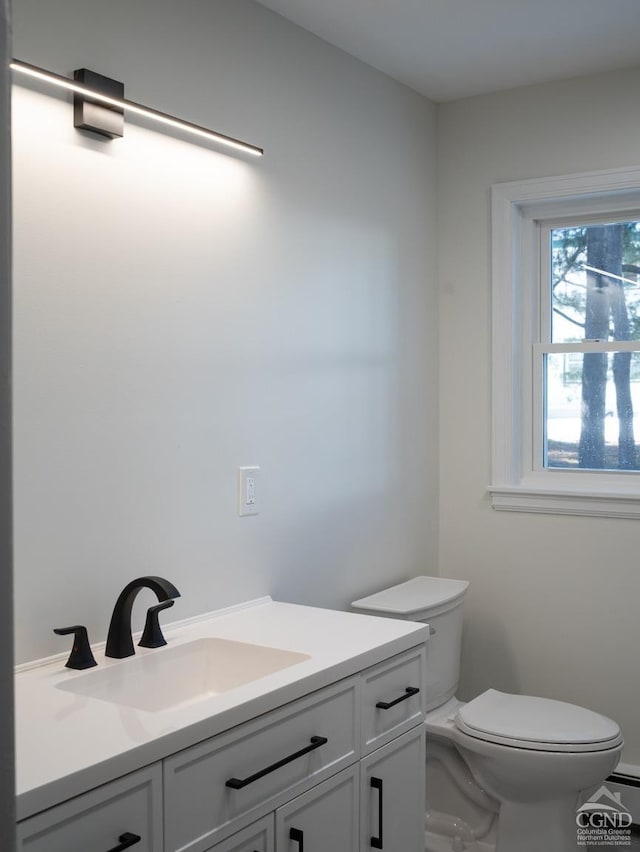 half bathroom featuring toilet, vanity, and a baseboard heating unit