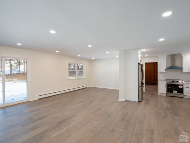unfurnished living room with baseboard heating, light wood-style flooring, recessed lighting, and baseboards