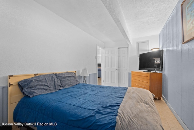 bedroom with a textured ceiling, tile patterned floors, and baseboards