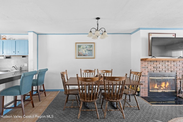 tiled dining room with an inviting chandelier, a sink, a textured ceiling, and a fireplace