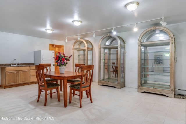 dining area featuring sink, rail lighting, and a baseboard radiator