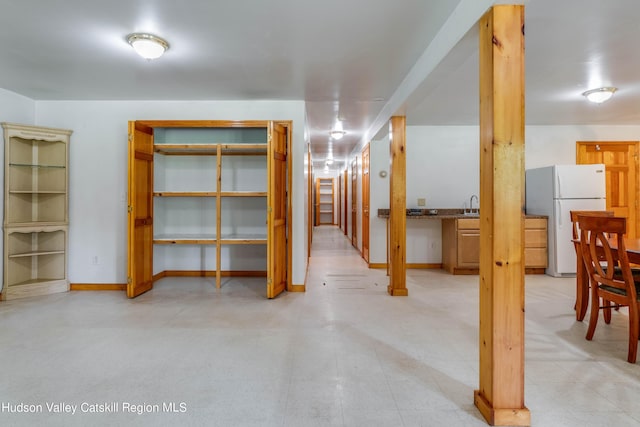 basement featuring white refrigerator and sink