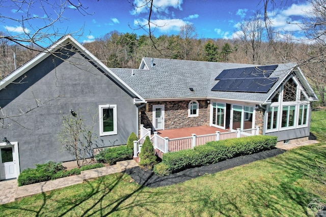 52 Hadley Dr, New Baltimore, NY 12087 - rear view of property with solar panels, a yard, a shingled roof, a wooden deck, and stucco siding