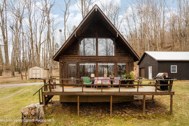 rear view of house featuring a shed, an outdoor structure, a lawn, and a deck