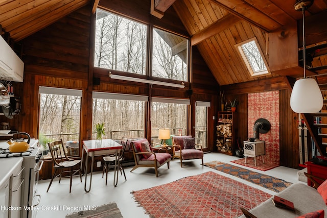 sunroom / solarium featuring beamed ceiling, a skylight, a wealth of natural light, and a wood stove