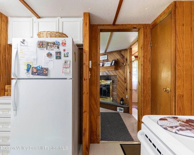 315 Begley Rd, Windham, NY 12496 - kitchen featuring freestanding refrigerator, wooden walls, a brick fireplace, a textured ceiling, and white cabinets