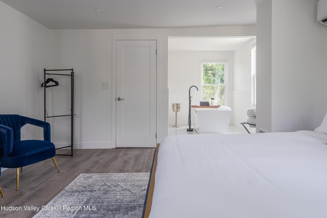 bedroom featuring wood-type flooring and a wall mounted air conditioner