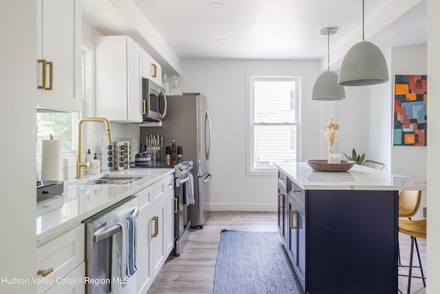 kitchen with white cabinetry, sink, hanging light fixtures, and appliances with stainless steel finishes