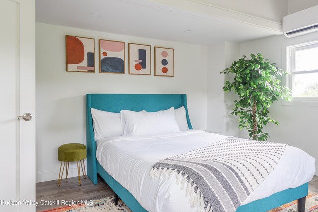 bedroom featuring hardwood / wood-style floors and a wall unit AC