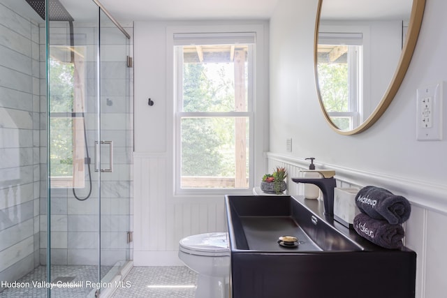 bathroom featuring tile patterned flooring, vanity, a shower with shower door, and toilet