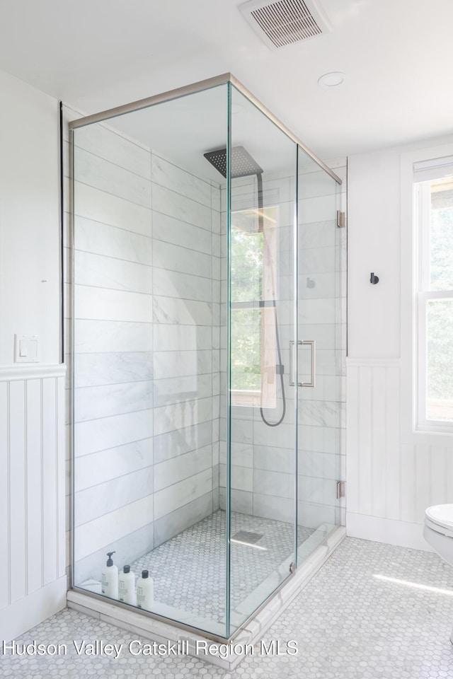 bathroom with tile patterned flooring, toilet, and a shower with door