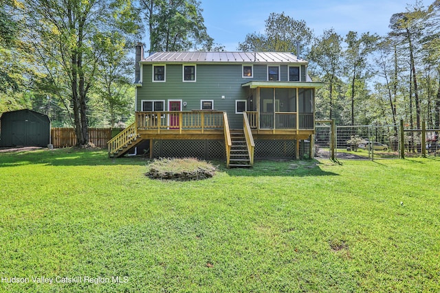 rear view of property featuring a lawn, a sunroom, a shed, and a deck