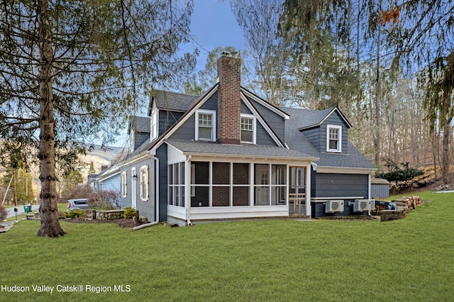 back of property featuring a chimney, a sunroom, a yard, and a shingled roof