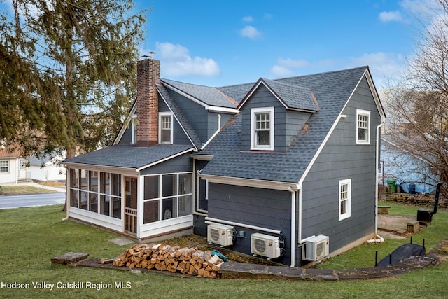 back of property featuring a yard, a sunroom, a shingled roof, and a chimney
