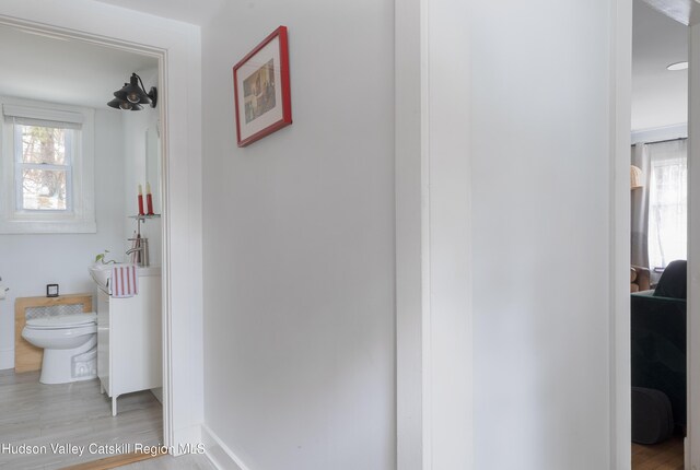 hallway featuring light wood-type flooring and baseboards