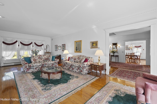living room with crown molding, baseboard heating, wood finished floors, and a chandelier