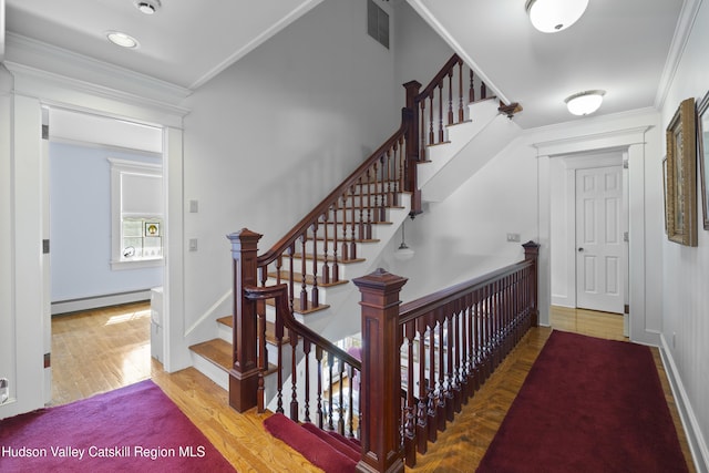 staircase featuring visible vents, ornamental molding, wood finished floors, and a baseboard radiator
