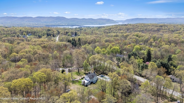 drone / aerial view with a water and mountain view and a forest view