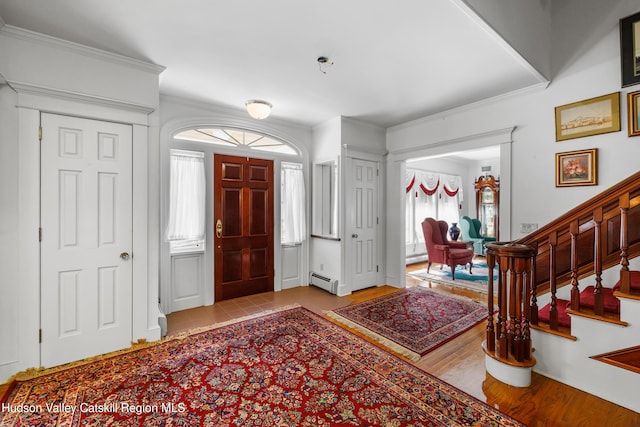 entrance foyer featuring crown molding, stairs, wood finished floors, baseboard heating, and a baseboard radiator