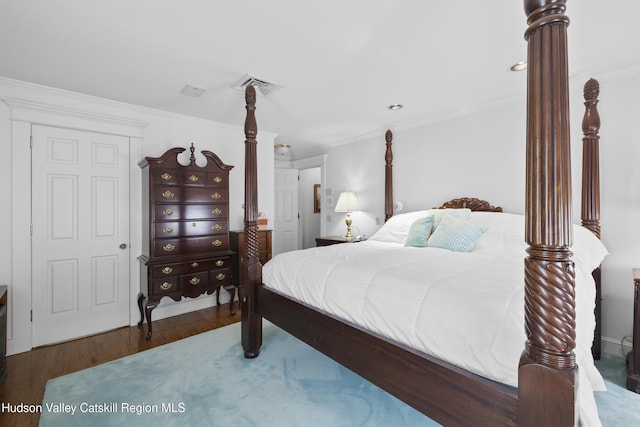 bedroom with crown molding, visible vents, and wood finished floors