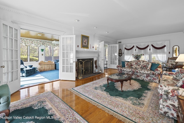 living area with crown molding, a healthy amount of sunlight, french doors, and wood finished floors