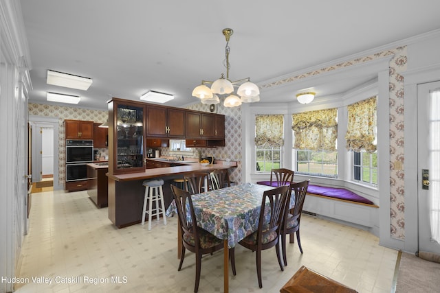 dining space with an inviting chandelier, wallpapered walls, a wealth of natural light, light floors, and ornamental molding
