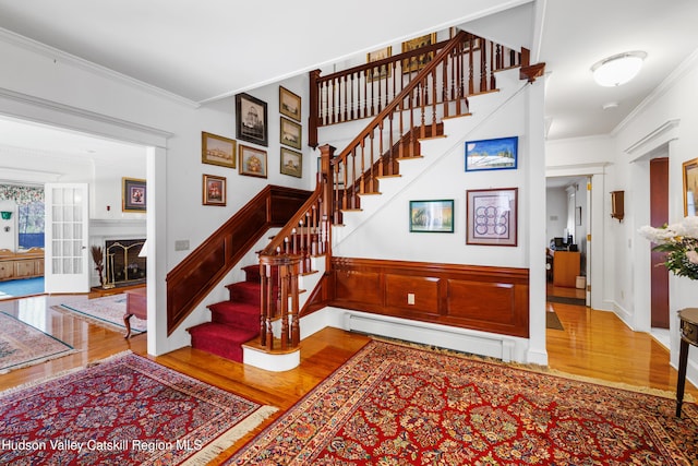 staircase featuring crown molding, baseboard heating, and wood finished floors