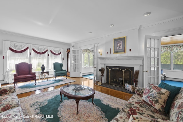living room featuring crown molding, wood finished floors, a baseboard radiator, recessed lighting, and a fireplace with flush hearth