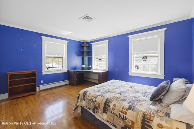 bedroom with crown molding, a baseboard heating unit, wood finished floors, and visible vents